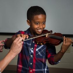 Image of Academy of Strings music lessons instructor assisting student playing violin
